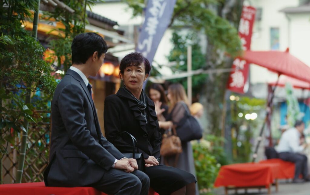 乃木憂助と櫻井司令が並んで話した場所は、深大寺門前のそば店「八起」の店先シーン