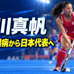 青いホッケーコートでボールを運ぶ女子日本代表の瀬川真帆選手