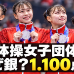 銀メダルを掲げる体操女子日本代表と、団体決勝の1.100点差を示す文字