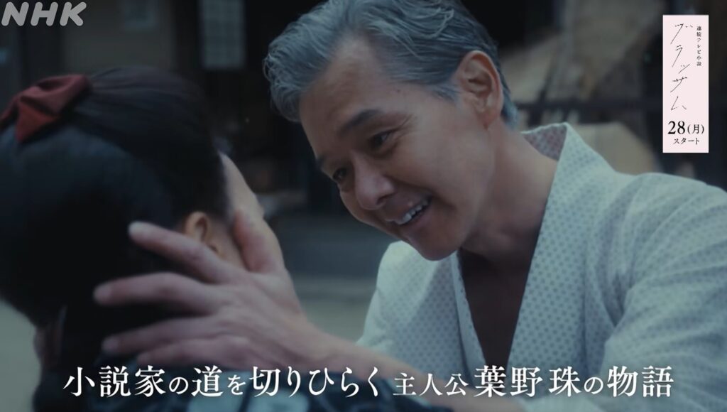 ドラマ『ブラッサム』で、父親の葉野清治が娘の顔を優しく両手で包み込み、温かい眼差しで微笑みかける印象的な一場面です。画面下部には「小説家の道を切りひらく 主人公 葉野珠の物語」という字幕テキストが添えられています。