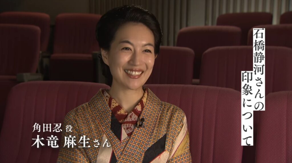 映画『ブラッサム』のインタビュー映像。角田忍役の木竜麻生さんが映画館の客席を背景に、満面の笑みで話している。画面左下に「角田忍 役 木竜麻生さん」、右上に「石橋静河さんの印象について」というテロップが表示されている。