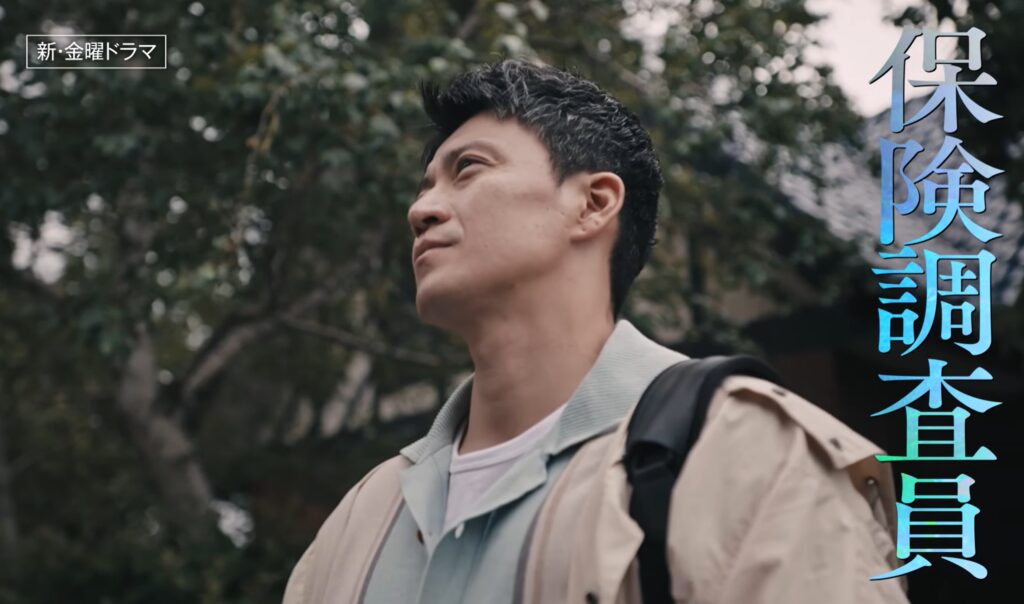 ドラマ『LOST10』のワンシーン。小栗旬演じるフリーの保険調査員・直が、野外でジャケットを羽織り、バックパックを背負いながら、木々を背景に何かを見上げている姿。