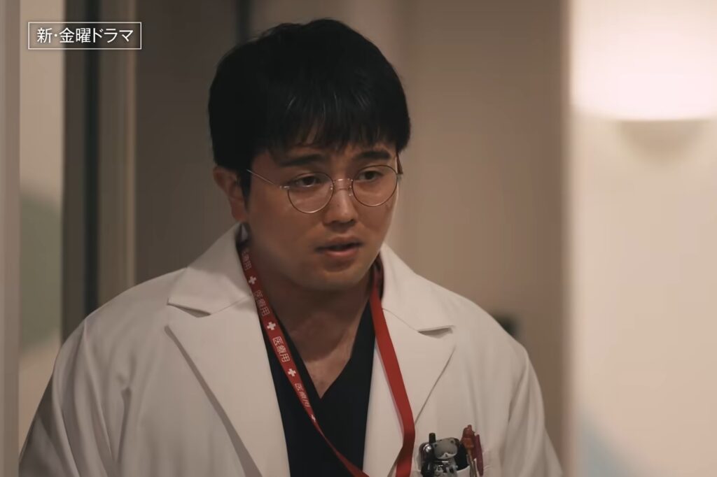 ドラマ『LOST10』で吉野役を演じる井口理さんが、眼鏡をかけて白衣と医療用ストラップを着用し、真剣な表情で佇む劇中ワンシーン。画面左上には「新・金曜ドラマ」のテキストが表示されている。