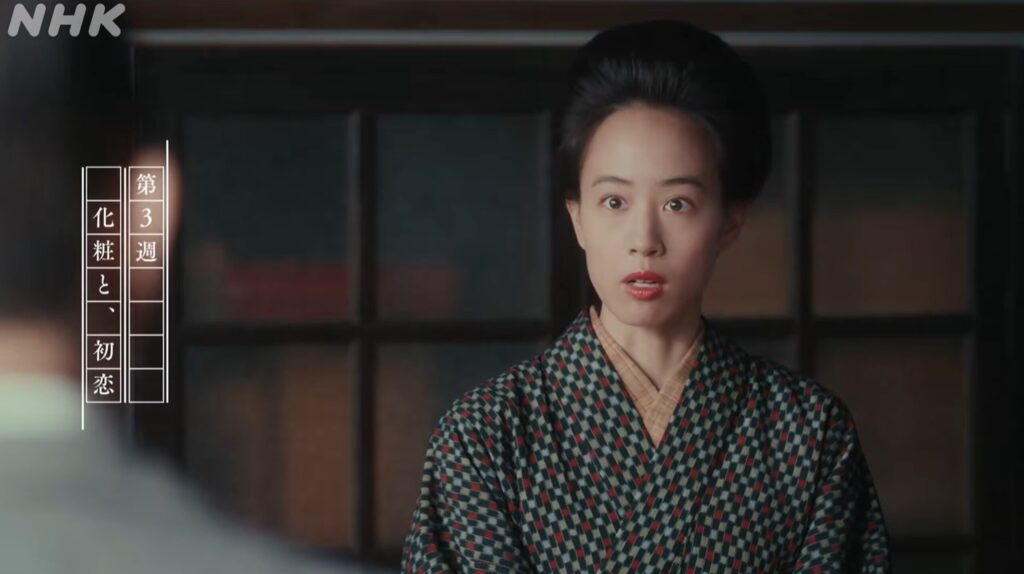 NHKドラマ『ブラッサムの珠はなぜ化粧を始めた?』より。伝統的な和服を着た若い女性が、前景の人物に対して驚いた表情を向けています。左上にはNHKのロゴ、左側には「第3週 化粧と、初恋」のテロップがあります。