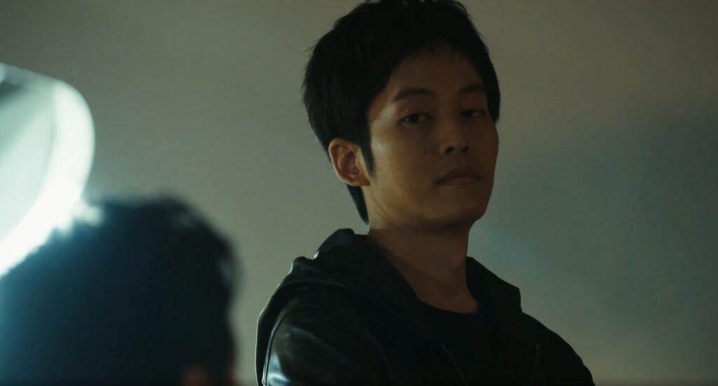 『VIVANT』第4話、夜の滑走路。黒須(松坂桃李)が点滴を準備する傍らで、乃木(F、堺雅人)が拘束された山本(迫田孝也)を冷徹な表情で見下ろし尋問している。背景には飛行機の機体が写っている。