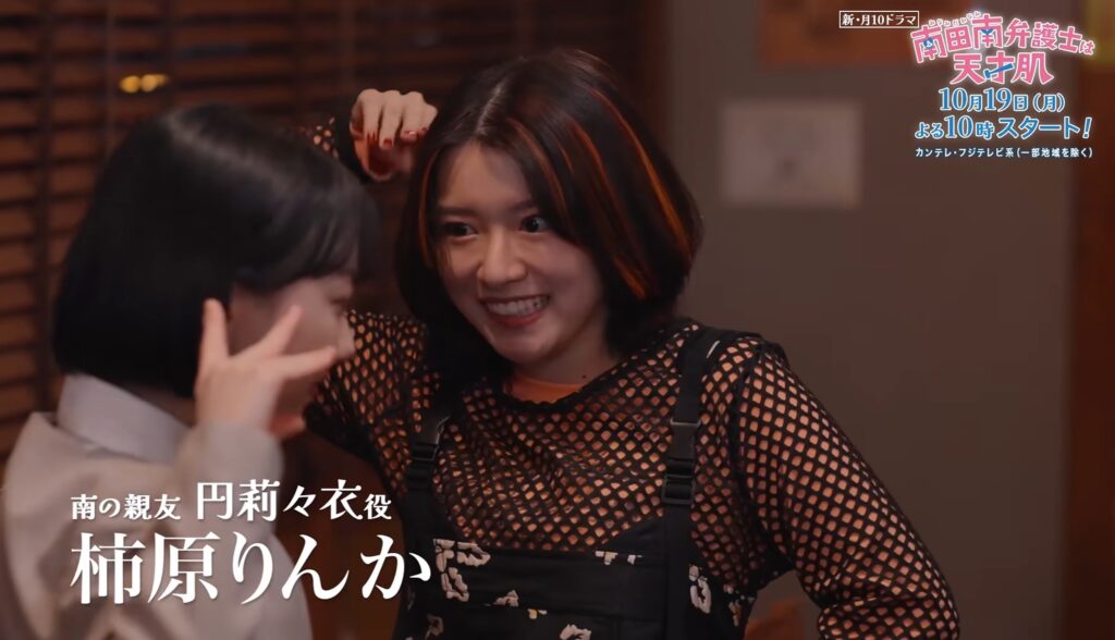 ドラマ『南田南弁護士は天才肌』のワンシーン。オレンジの髪メッシュが印象的な円莉々衣役の柿原りんかさんが、手前でポーズをとる人物に向かってお茶目な笑顔を見せている。画面左下にはキャスト名、右上には番組ロゴを表示。
