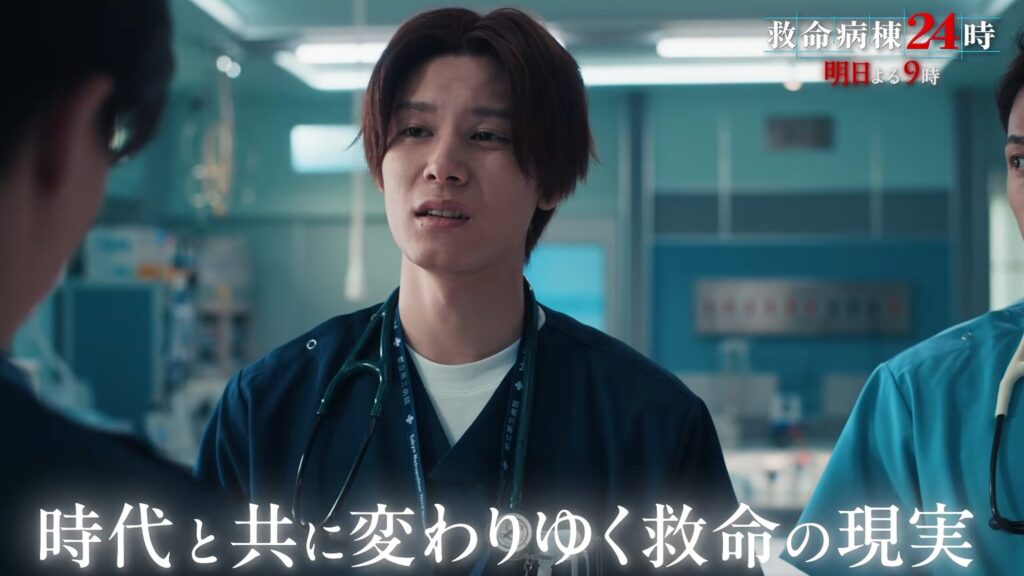 ドラマ『救命病棟24時』のワンシーン。青いスクラブを着用し聴診器を首にかけた萩原利久さんが、真剣かつ葛藤を浮かべた表情で相手を見つめている。画面下部には「時代と共に変わりゆく救命の現実」という白いテロップを表示。
