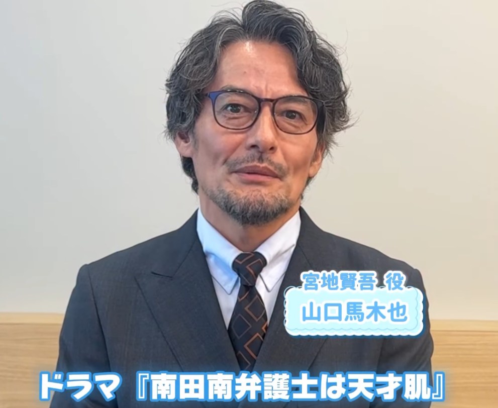 ドラマ『南田南弁護士は天才肌』で宮地賢吾役を演じる、スーツ姿の俳優・山口馬木也さんのポートレート。眼鏡とひげが特徴。画像には役名とドラマ名のテキストが入っている。