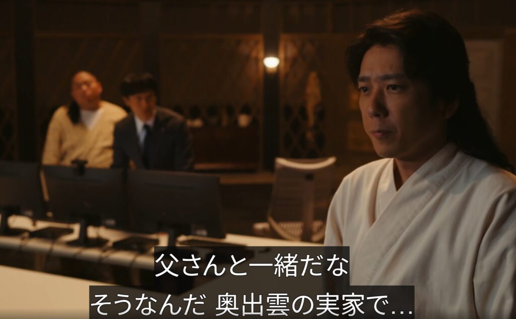 ラマ『VIVANT』のワンシーン。前景に和装姿で座り、「父さんと一緒だな」「奥出雲の実家で...」と字幕付きで話す乃木。背景にはPCモニターと2人の男性。