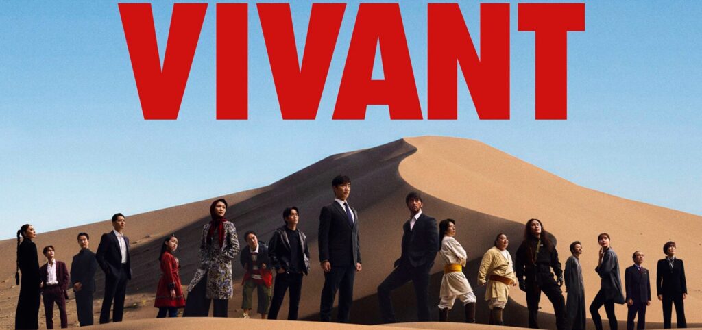 青空と大きな砂漠の砂丘を背景に、中央に大きく赤字で「VIVANT」のロゴが配置され、その下で主要キャストたちが真剣な表情でずらりと立ち並んでいるドラマのメインビジュアル。