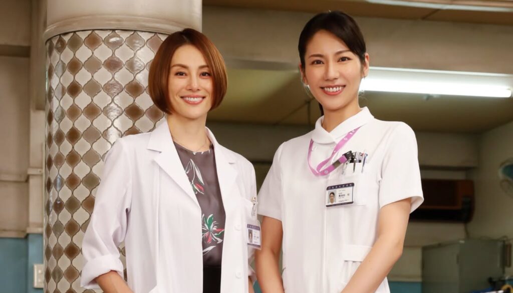 ドラマ『ドクターX』より、白衣を着た主演の米倉涼子と、白いナース服姿で笑顔を見せる松下奈緒が並んで立つ姿。看護師・那須田灯役として登場した場面の2ショット画像です。