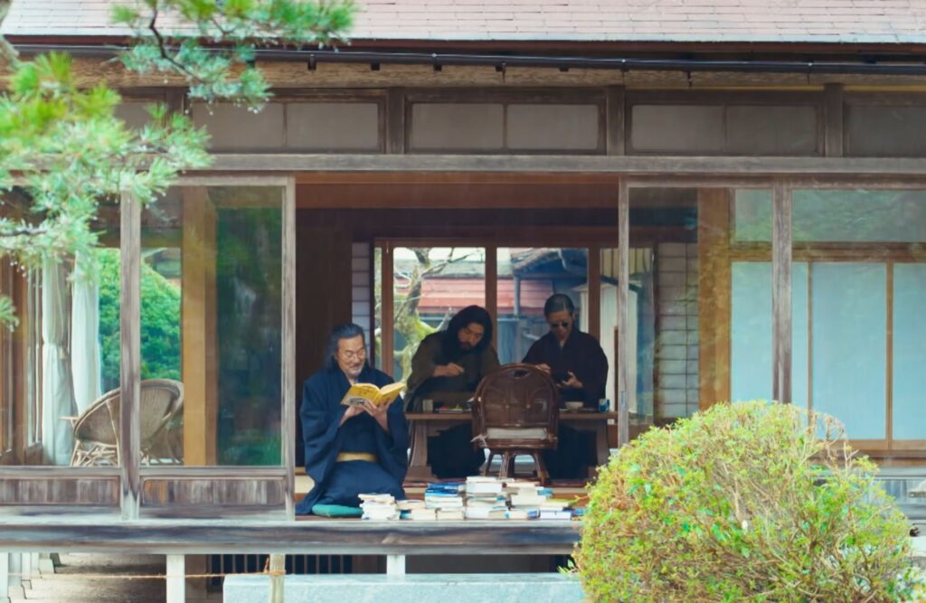 ドラマ『VIVANT』のワンシーン。奥出雲の日本家屋の縁側で、山積みにされた本を前に楽しそうに読書をするノゴーン・ベキと、奥の部屋で過ごすバトラカ、ピヨの姿。