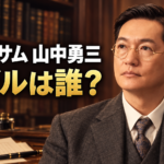 書棚と原稿用紙を背景に、眼鏡とスーツ姿の山中勇三を描き、「ブラッサム 山中勇三」「モデルは誰？」と添えたイメージ画像。